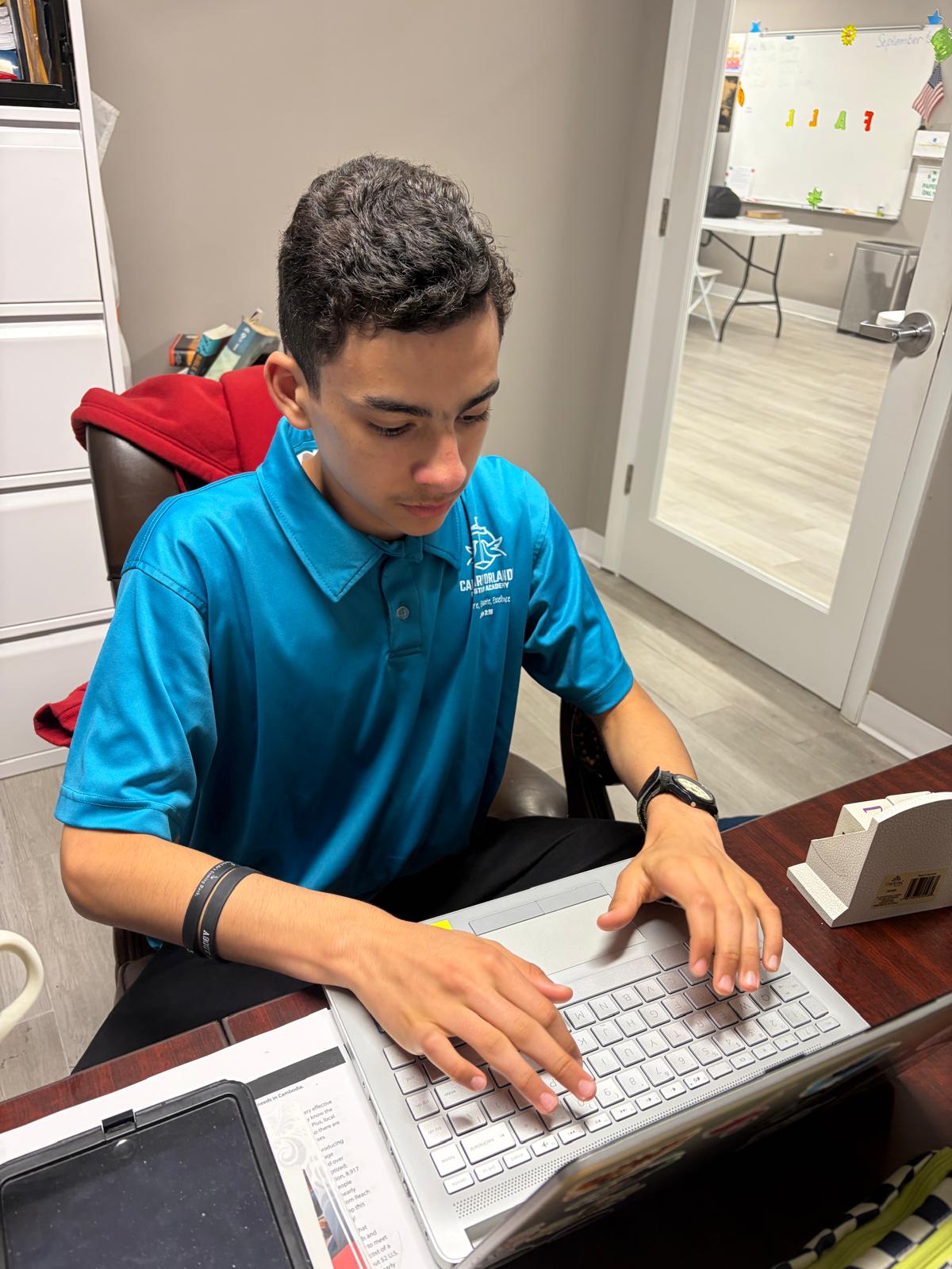 COCA student working on a laptop in the classroom